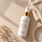 Frasco da Bruma Clareadora Dermatológica MoonLit 120 ml deitado sobre linho bege, ao lado de uma toalha felpuda, um ramo seco e um pratinho de cerâmica, com luz de manhã.