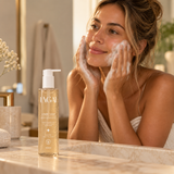 Mulher lavando o rosto com espuma do Sabonete Facial Lunar Clear 300ml da Lagai, frasco com gel âmbar na bancada do banheiro.